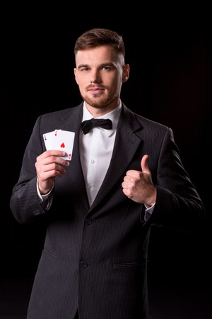 man in a suit posing with cards for gambling on black backgroundの写真素材