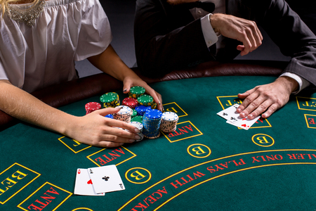 couple playing poker at the table. The blonde girl and a guy in a suit. close up hands.の写真素材
