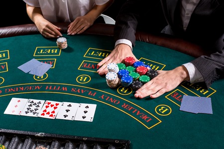 couple playing poker at the table. The blonde girl and a guy in a suit. close up hands. bets all-in
