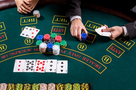 couple playing poker at the table. The blonde girl and a guy in a suit. close up hands. man bets chipsの写真素材
