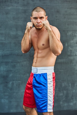 Boxer shorts in athletic training outdoors. He stands in a fighting stance and looking at the camera The young man works off a blowの写真素材