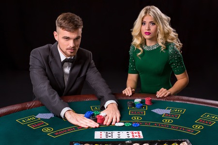 couple playing poker at the green table. The blonde girl and a guy in a suit. all-in bets chipsの写真素材
