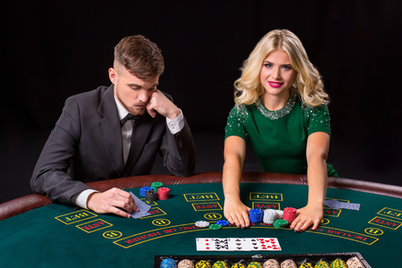 couple playing poker at the green table. The blonde girl and a guy in a suit. all-in bets chipsの写真素材