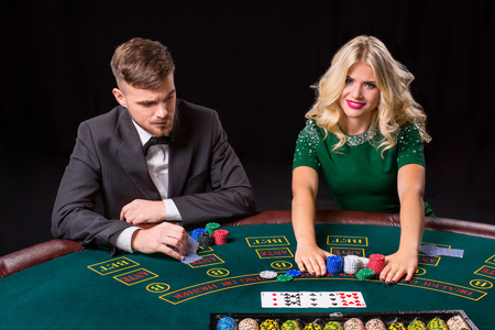 couple playing poker at the green table. The blonde girl and a guy in a suit. all-in bets chipsの写真素材