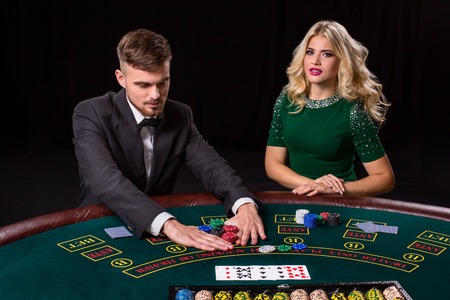couple playing poker at the green table. The blonde girl and a guy in a suit. all-in bets chipsの写真素材
