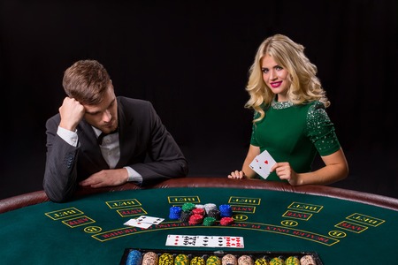 couple playing poker at the green table. The blonde girl and a guy in a suit. happy win, two acesの写真素材
