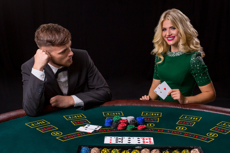 couple playing poker at the green table. The blonde girl and a guy in a suit. happy win, two acesの写真素材