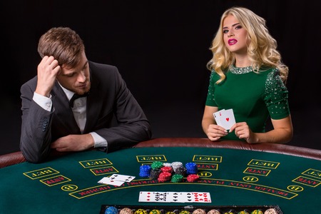 couple playing poker at the green table. The blonde girl and a guy in a suit. happy win, two acesの写真素材