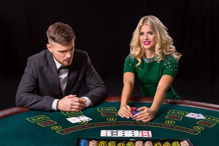 couple playing poker at the green table. The blonde girl and a guy in a suit. happy winの写真素材