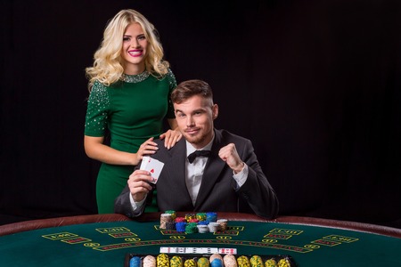 couple playing poker at the green table. The blonde girl and a guy in a suit. happy win, twoの写真素材