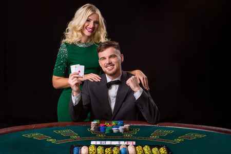 couple playing poker at the green table. The blonde girl and a guy in a suit. happy win, twoの写真素材