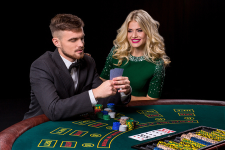 couple playing poker at the green table. The blonde girl and a guy in a suit.の写真素材