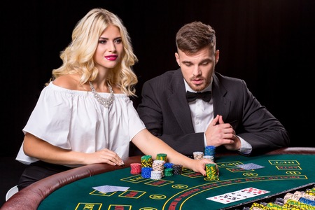 couple playing poker at the green table. The blonde girl and a guy in a suit. chips betsの写真素材