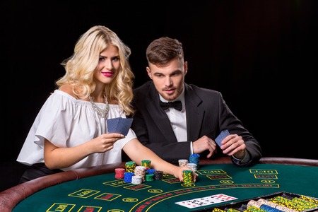 couple playing poker at the green table. The blonde girl and a guy in a suit. chips betsの写真素材