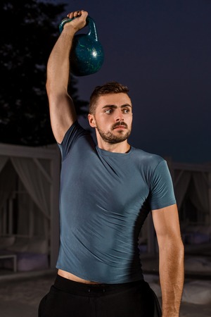 Muscular man working with weights at outdoor. sport exercises with kettlebell street workoutの写真素材