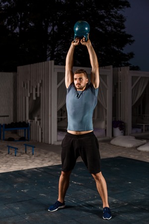 Muscular man working with weights at outdoor. sport exercises with kettlebell. street workoutの写真素材