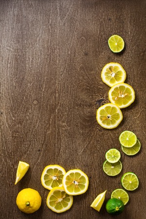 A sliced lemon, lime on a slate and wooden counter top background forming a page borderの写真素材