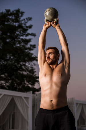 Muscular man working with weights at outdoor. sport exercises with kettlebell. street workoutの写真素材