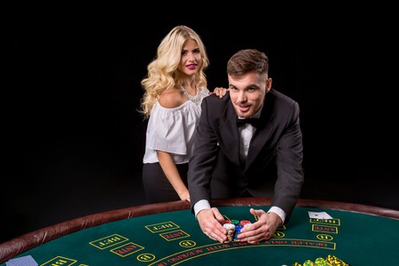 View of young, confident, man with the lady while he's playing poker game. They both look at the camera and smilingの写真素材