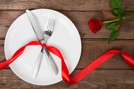 Valentines day table setting with plate, fork, knife, ribbon and rose.   backgroundの写真素材