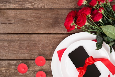 Top view closeup of romantic dinner serving with a bouquet  red roses and present above the white plateの写真素材