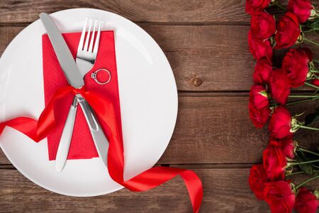 Valentines day table setting with plate, fork, knife, ring, ribbon and roses.   backgroundの写真素材