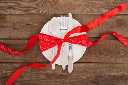 valentines day background, white plate, fork, knife, tape hearts on old wooden table,の写真素材