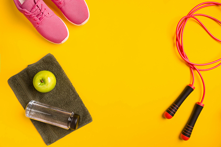 Athletes set with female clothing, skipping rope and bottle of water on yellow backgroundの写真素材