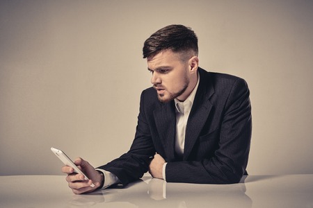 Handsome young man talking on the mobile phone while sitting at his working place in officeの写真素材