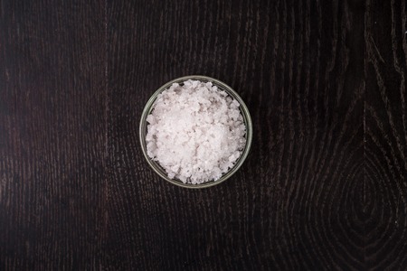 Salt in a glass bowl - top view. On a black background. Still life. Copy spaceの写真素材