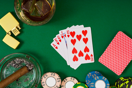 Set to playing poker with cards and chips on green table, top view