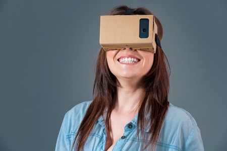Woman using a new virtual reality headset on grey backgroundの写真素材