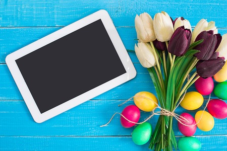 Easter eggs and tulips on blue rustic wooden planksの写真素材