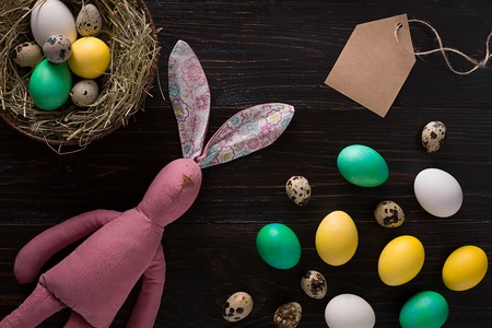 Easter eggs in nest and pink rabbit on a black background