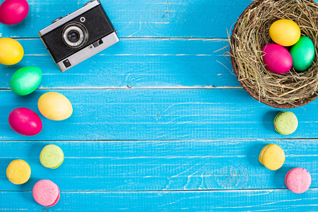 Colorful easter egg in nest on blue wood board.