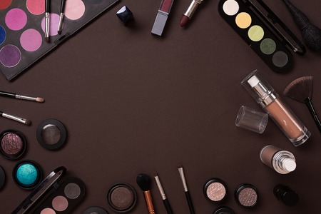The women's cosmetics set on a brown background, modern woman. Brush for makeup, eye shadow, view from above. Copy spaceの写真素材