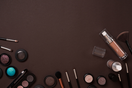 The women's cosmetics set on a brown background, modern woman. Brush for makeup, eye shadow, view from above. Copy spaceの写真素材