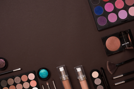 The women's cosmetics set on a brown background, modern woman. Brush for makeup, eye shadow, view from above. Copy spaceの写真素材