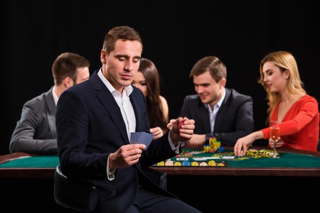 Poker players in casino with cards and chips on black backgroundの写真素材
