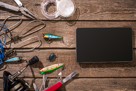 Accessories for fishing on the background of wood. Reel, fishing line, float, net hooks, lures for fishing. Top view. Still life. Copy spaceの写真素材