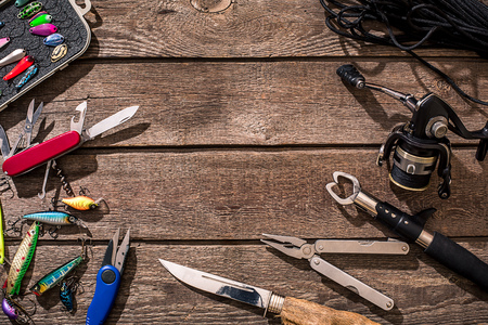 Accessories for fishing on the background of wood. Reel, fishing line, float, net hooks, lures for fishing. Top view. Still life. Copy spaceの写真素材