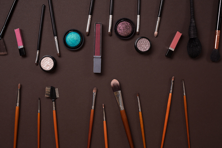 The women's cosmetics set on a brown background, modern woman. Brush for makeup, eye shadow, view from above. Copy spaceの写真素材