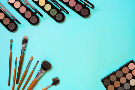 The women's cosmetics set on a blue background, modern woman. Brush for makeup, eye shadow, view from above. Copy spaceの写真素材