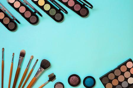 Make up essentials. Set of professional make up brushes, creams and shadows in jars on blue background. Place for your text or logo. Ideal for beauty blog.の写真素材