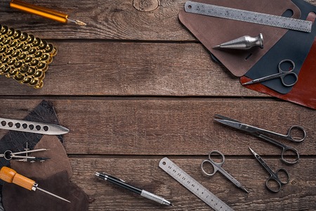 Leather craft or leather working. Leather working tools and cut out pieces of leather on work desk. Still life. Copy space. Top viewの写真素材