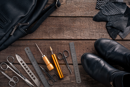Leather craft or leather working. Leather working tools and cut out pieces of leather on work desk. Still life. Copy space. Top viewの写真素材