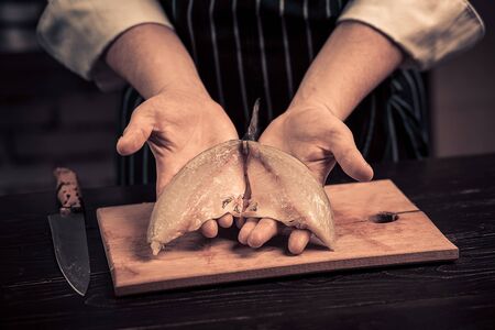 Chef cutting the fish on a boardの写真素材