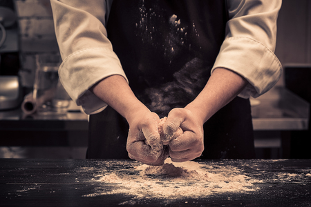 The chef makes dough for pasta on a wooden tableの写真素材