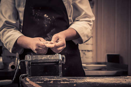 The chef makes dough for pasta on a wooden tableの写真素材