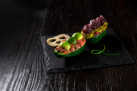 Salmon tartare and avocado salad on a black backgroundの写真素材